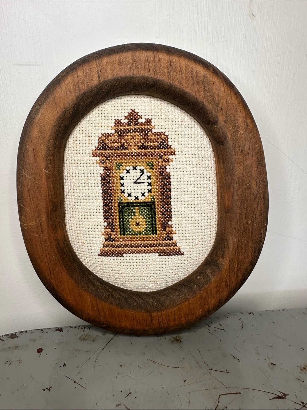 Vintage cross-stitch grandfather clock in oval wooden frame